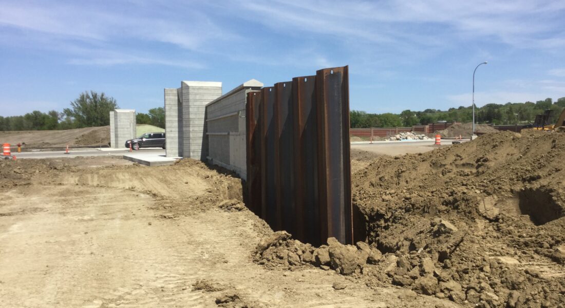 Steel sheet piling, dirt piles, and partly built concrete structure.