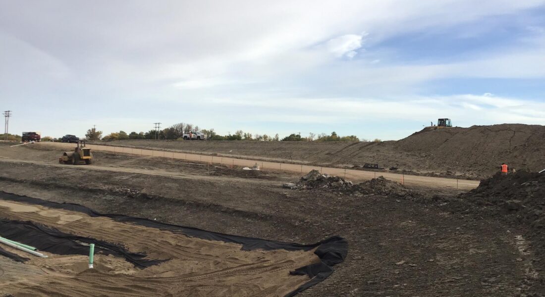 Bulldozers move dirt at a construction site under clouds.