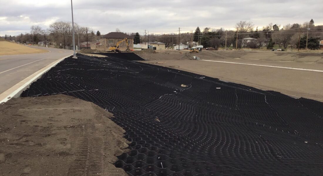 Construction site with geogrid, curb, clouds, and project text overlay.