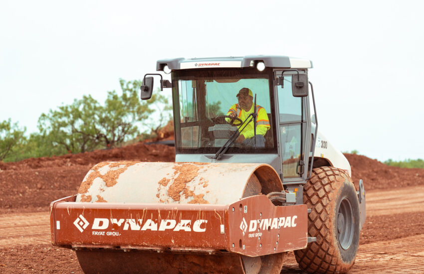 Worker uses Dynapac compactor to smooth dirt at site.