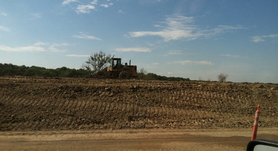 Bulldozer on a dirt site, tire tracks and safety cone.