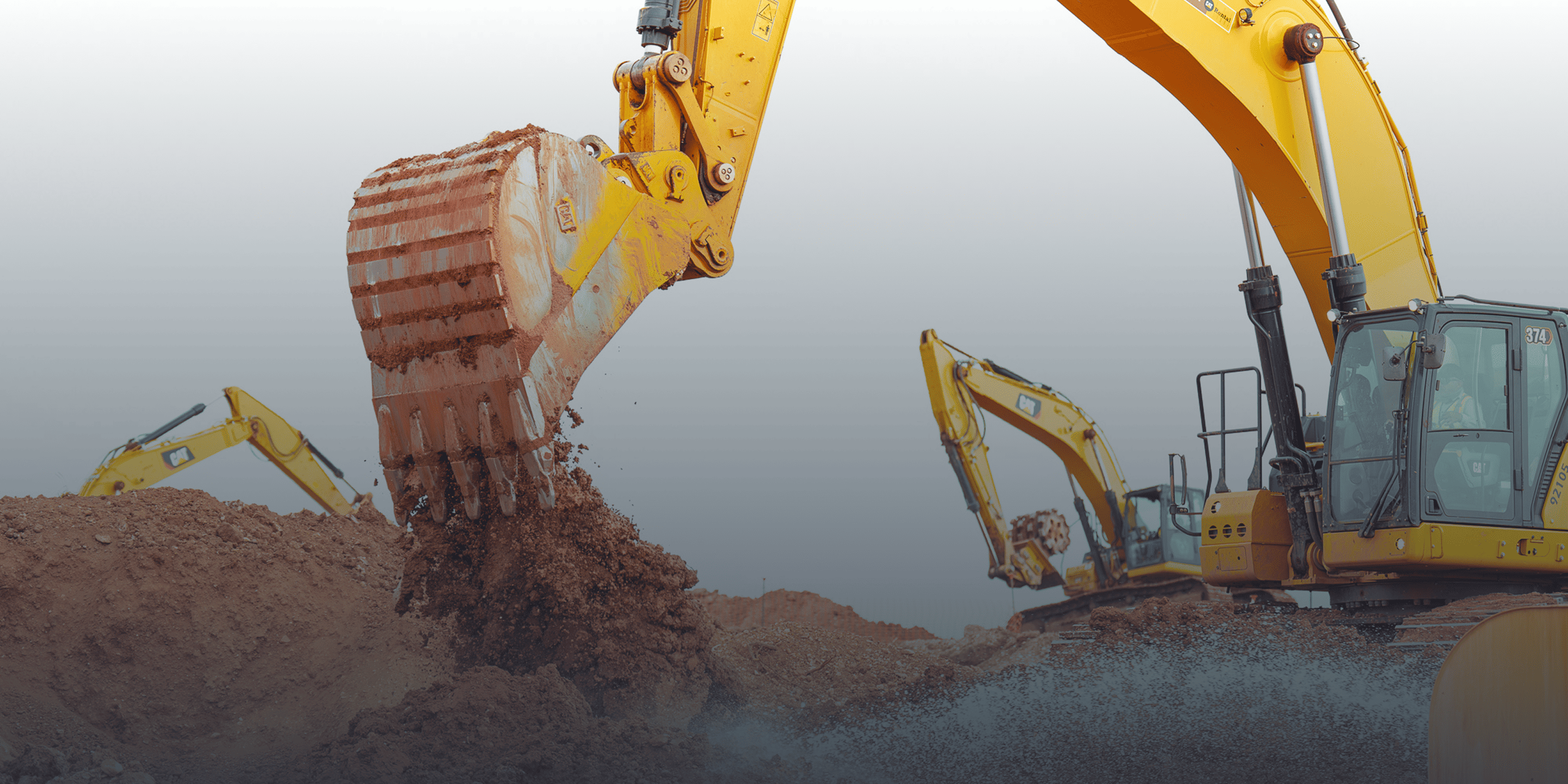 Yellow excavators digging and moving soil at construction site.