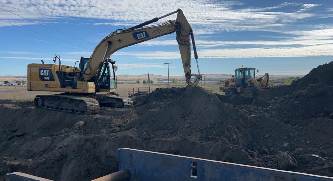 Excavator and loader move dirt on construction site.