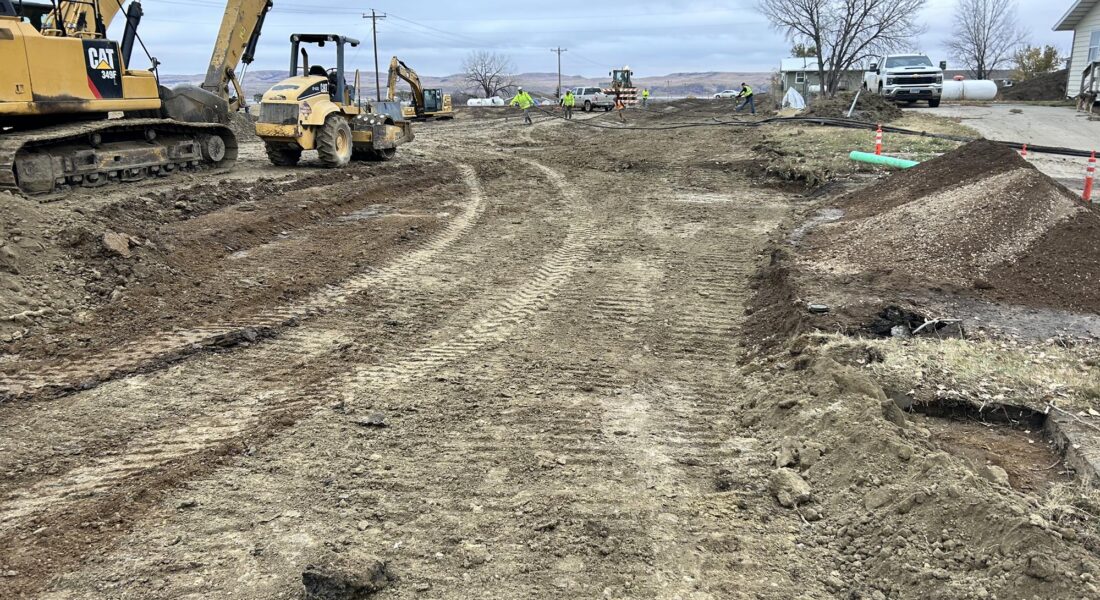 Heavy machinery and workers on a dirt road construction site.
