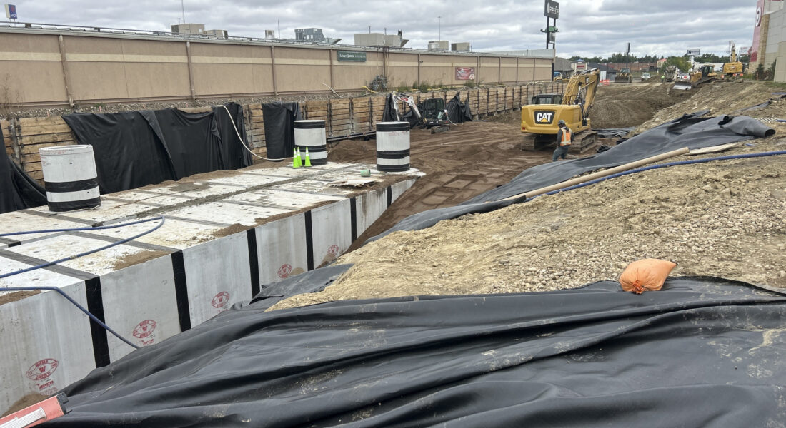 Construction site with concrete blocks, black tarps, equipment; info overlay.