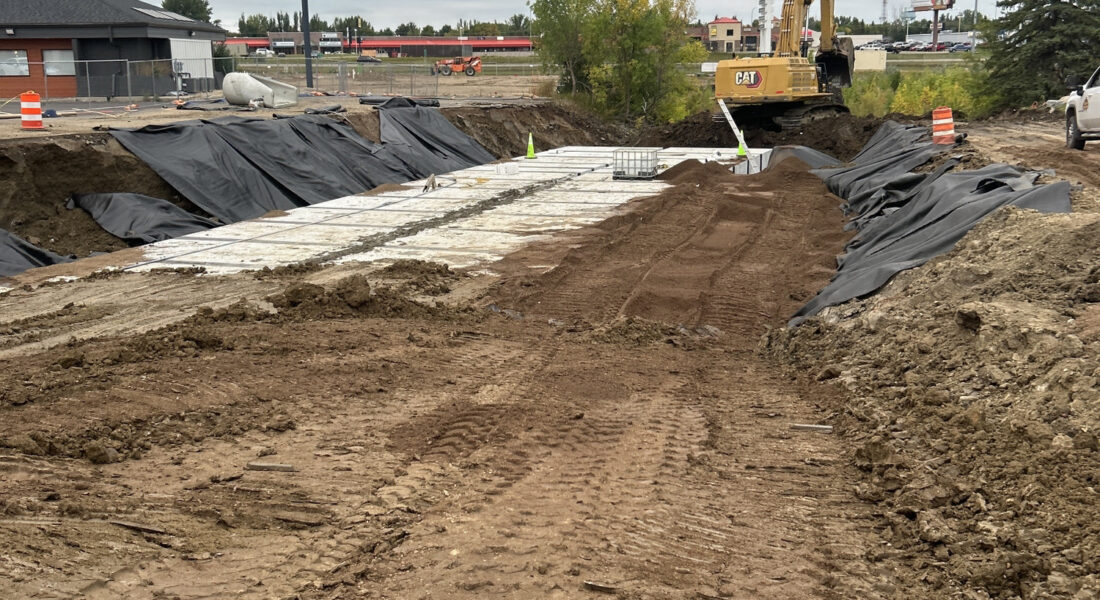 Minot, ND construction site: excavator, dirt piles, cones, plastic cover.