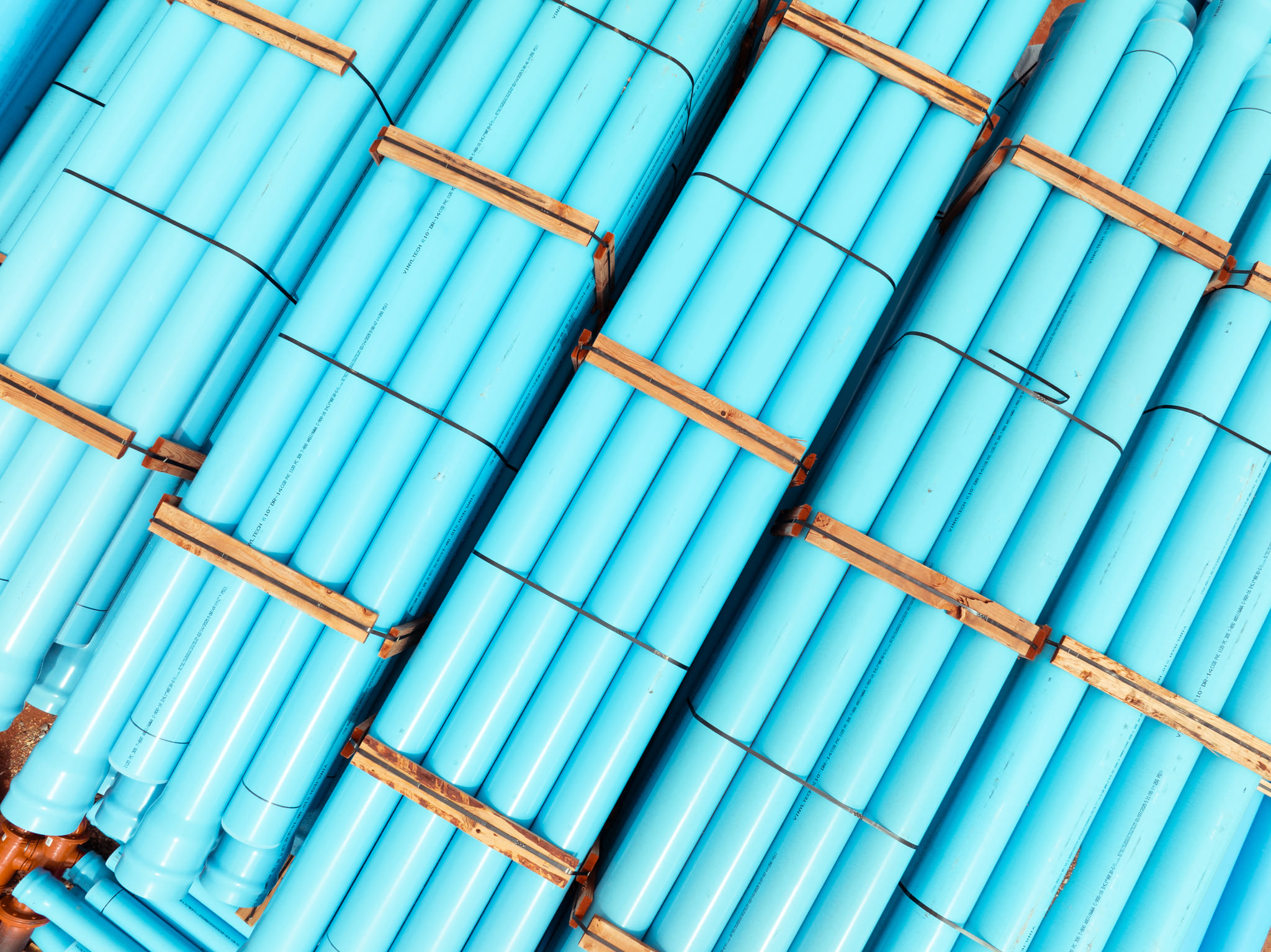 Aerial view of blue PVC pipes stacked in rows.